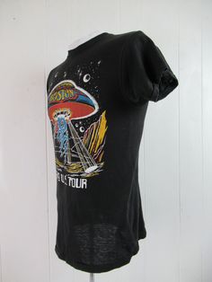 "Vintage 1970s black cotton rock and roll band concert tour t shirt with multi color glitter graphics. Front has a UFO and Boston 1979 U.S. Tour. Back has band members. Size small. Actual measurements are: 35\" around the chest 35\" around the waist 15\" shoulder seam to shoulder seam 27\" overall length In excellent condition." Rock And Roll T-shirt With Band Logo For Summer, Fitted T-shirt With Vintage Print And Short Sleeves, Fitted Short Sleeve T-shirt For Festivals, Rock And Roll Band Logo T-shirt For Summer, Rock And Roll Style T-shirt For Summer Streetwear, Vintage Fitted T-shirt With Letter Print, 90s Vintage Print Black T-shirt, Rock And Roll Cotton Graphic T-shirt, Cotton Rock And Roll T-shirt With Graphic Print