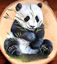 a panda bear sitting on top of a wooden bowl with bamboo leaves in it's paws