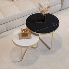 two black and white tables sitting on top of a carpeted floor next to a couch