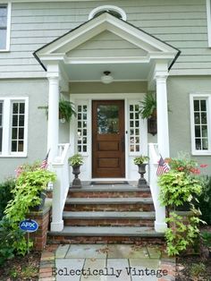 the front door of a house with potted plants on either side and steps leading up to it