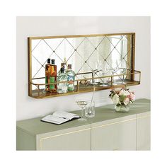 a mirror on the wall above a dresser with bottles and glasses in front of it