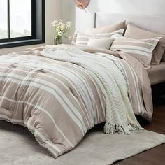 a bedroom with a large bed covered in beige and white striped comforter, pillows and blankets