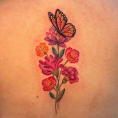 a butterfly and flowers tattoo on the back of a woman's upper back shoulder