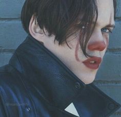 a close up of a person wearing a black leather jacket and red lipstick with blood on his face