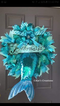 a mermaid wreath hanging on a door with the name mermaid's written on it