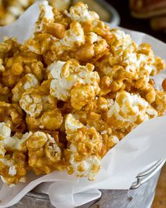 a bucket filled with caramel popcorn sitting on top of a wooden table