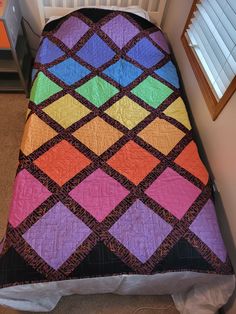 a multicolored quilt on top of a bed in a child's room