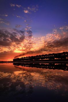 the sky is reflected in the water at sunset