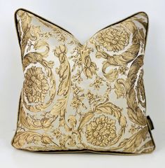 a gold and white decorative pillow on a white background with a black zippered closure