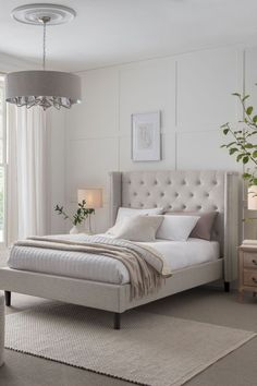 a bedroom with a bed, nightstands and two lamps on either side of the bed