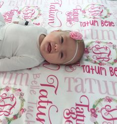 a baby laying on top of a pink and white blanket