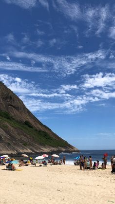 many people are on the beach with umbrellas