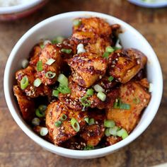 a white bowl filled with chicken and green onions