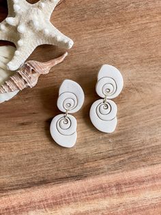 two white seashells sitting on top of a wooden table next to a starfish