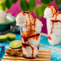 two cups filled with ice cream and toppings next to lime slices on a cutting board