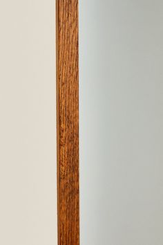 a mirror with a wooden frame in the corner and a white wall next to it