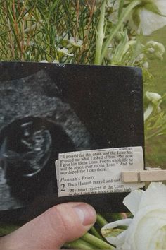 a hand holding a piece of paper with an image of a gorilla on it and flowers in the background