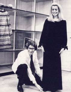 a man kneeling down next to a woman in front of a display case with clothes on it