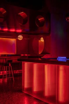 a bar with red and blue lights in the corner, next to two stools