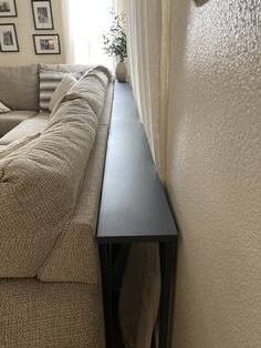 a living room with a couch, table and pictures hanging on the wall behind it