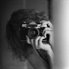 a woman taking a selfie in front of a mirror while holding a camera up to her face