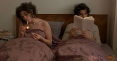 a man and woman laying in bed reading books