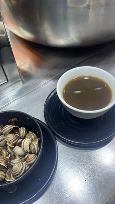 a bowl of clams sits next to a plate of mussels on a counter