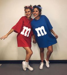 two women dressed in matching m and m t - shirts pose for a photo together