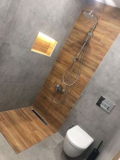 a bathroom with a toilet, shower head and wooden flooring on the side wall