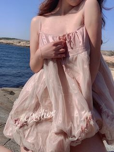 a woman in a pink dress standing by the water