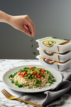 a plate with rice, peas and tomatoes on it next to three boxes of food