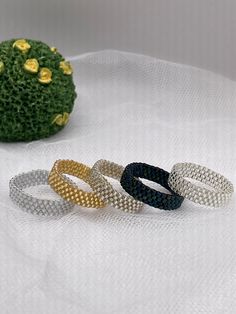 four different colored bracelets sitting on top of a white cloth covered table next to a cactus