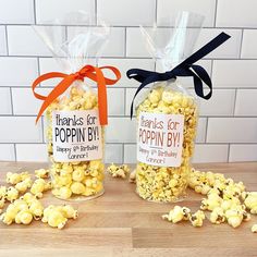 two bags filled with popcorn sitting on top of a wooden table next to each other