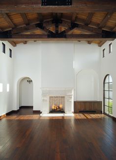 an empty living room with wood floors and fireplace in the center, surrounded by arched windows