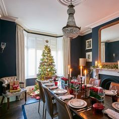 a dining room table set for christmas dinner with candles and decorations on the table in front of it