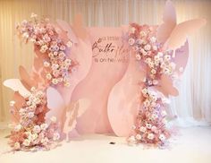 a pink backdrop with flowers and butterflies on the side for a baby's first birthday