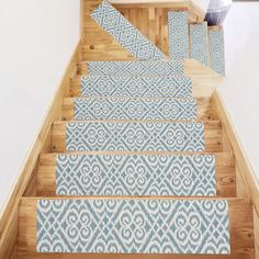 the stair treads are decorated with blue and white rugs on wooden steps in a home