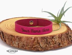 a pink rubber bracelet that says your name here on it, with an air plant in the background