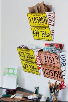 there are two license plates hanging from the wall above a desk with pens, pencils and markers