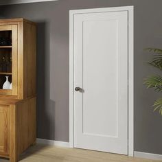 a wooden cabinet sitting in the corner of a room next to a potted plant