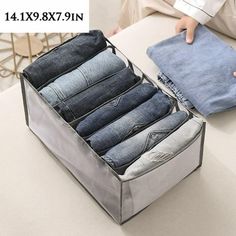 an open suitcase filled with jeans sitting on top of a table next to a person