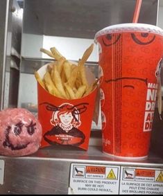 some french fries and a drink are on a counter in a fast food restaurant,