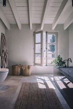 a bath room with a tub a sink and a window next to a rug on the floor