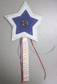 a blue and white star shaped pinwheel hanging from a string on a gray wall