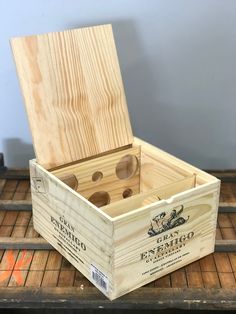 a wooden box with glasses in it sitting on top of a tile floor next to a wall