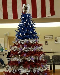 a decorated christmas tree with red, white and blue decorations in front of an american flag