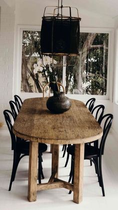 a wooden table with chairs around it and a vase on top of the dining room table