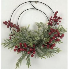 a wreath with red berries and greenery hanging on a wall