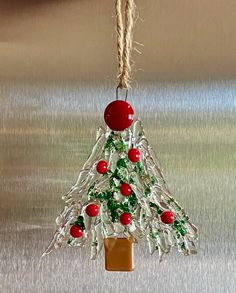 a small christmas tree made out of plastic bottle caps and beads hanging from a rope