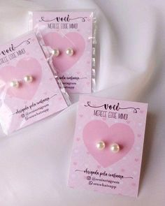 two pink heart shaped buttons with white pearls on them sitting in front of a package